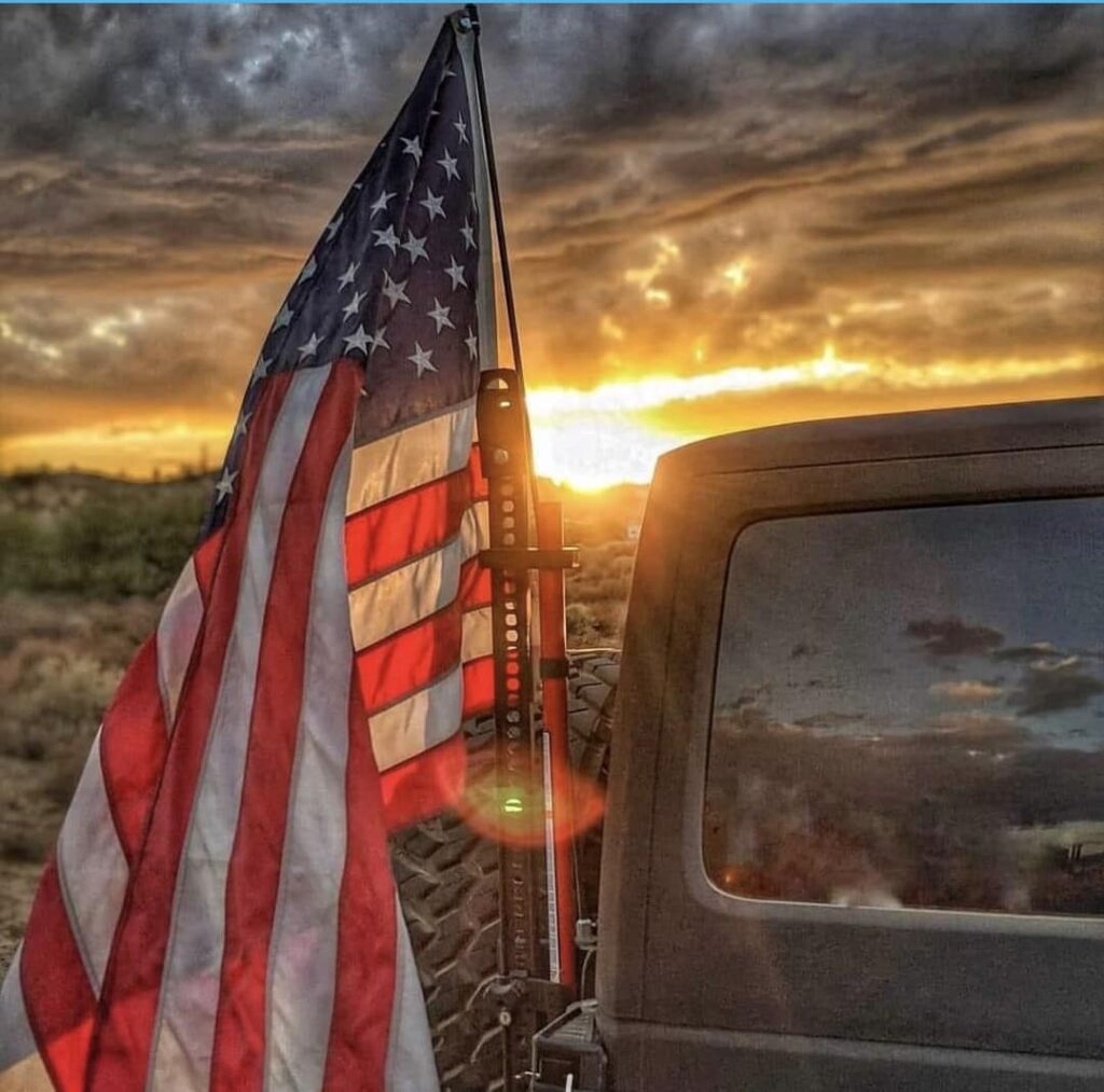 U.S. flag mounted on a vehicle with sunset in the background